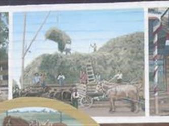 A mural of a man sitting at a table, a livestock market, and a meat market building