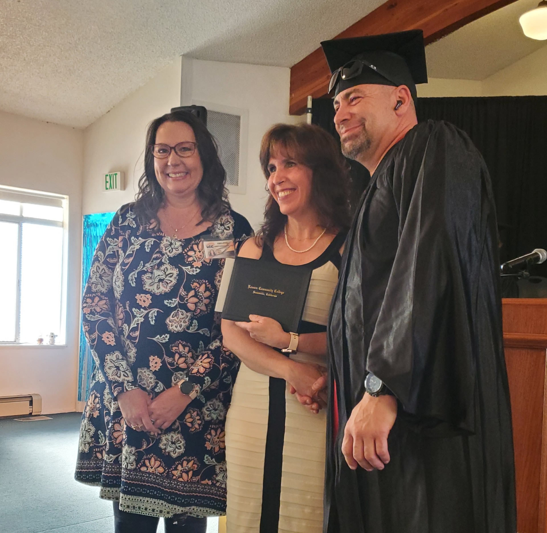 Two people presenting diploma to adult education graduate. 