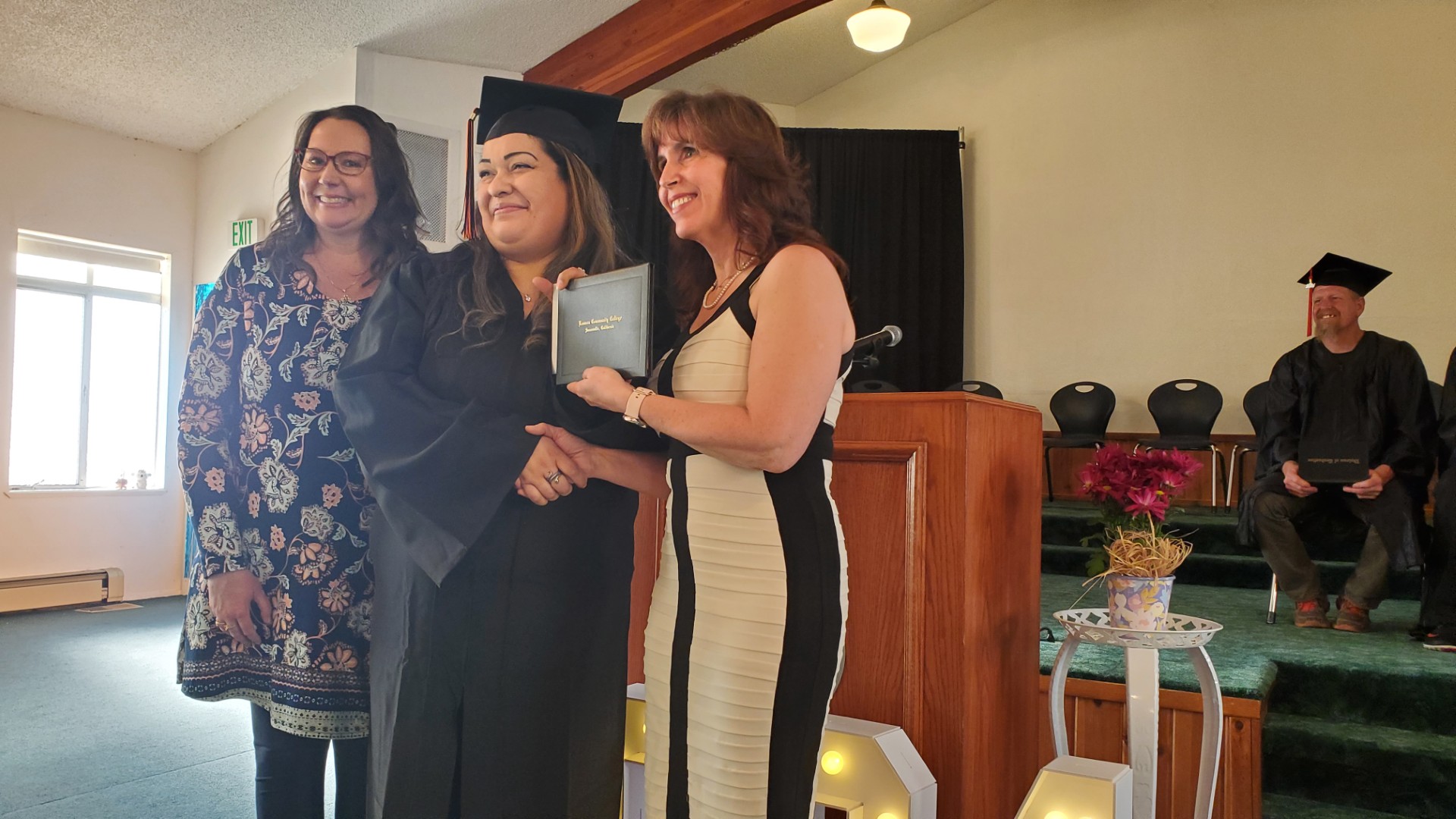 Two people presenting diploma to adult education graduate. 